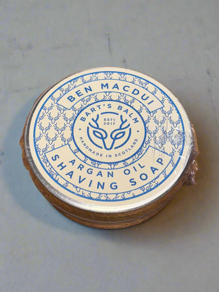 Round shaving soap bar with blue label on a wooden surface